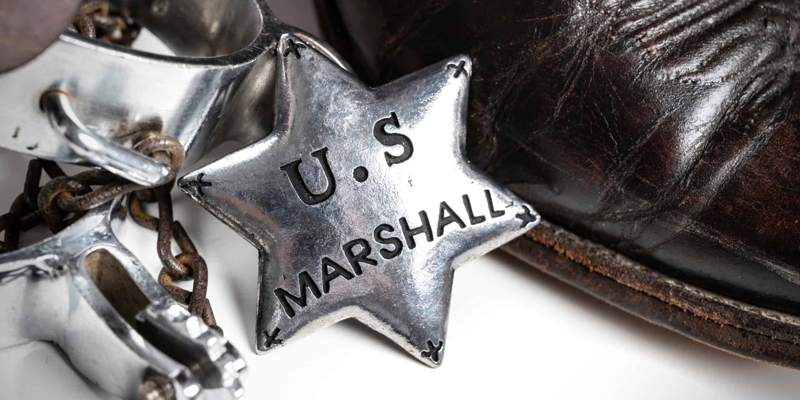 A group Of items old West themed items including United States Marshalls badge with cowboy boots and spurs
